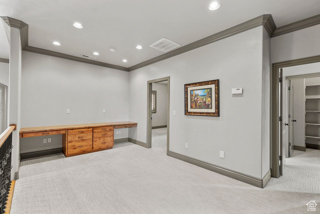 Unfurnished office featuring ornamental molding, light colored carpet, built in desk, and recessed lighting