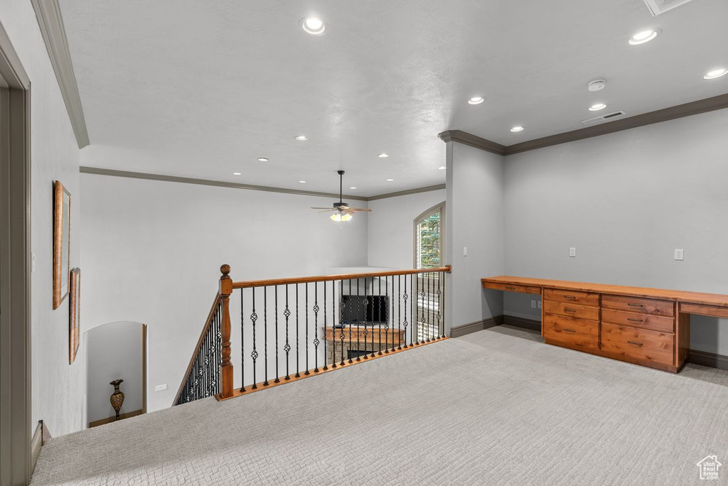 Spare room with ornamental molding, ceiling fan, recessed lighting, built in desk, and carpet