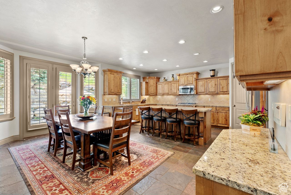 Dining space with a chandelier, recessed lighting, and stone tile flooring