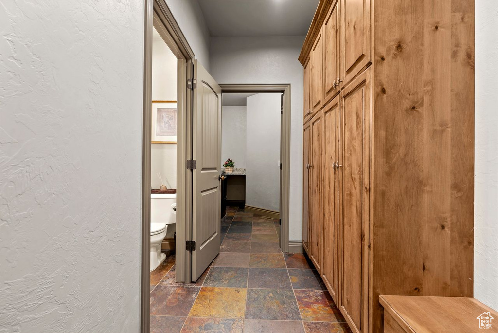 Hall featuring stone tile flooring and a textured wall