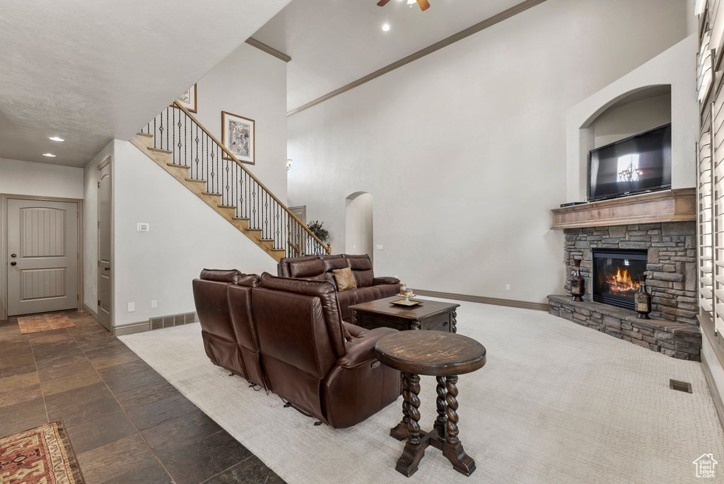 Living room featuring a fireplace, stairs, a high ceiling, recessed lighting, and stone finish flooring