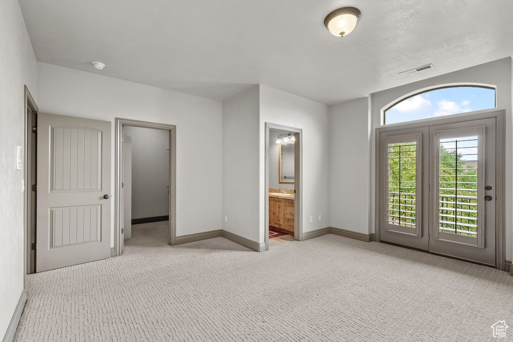 Unfurnished bedroom with light carpet, access to outside, and ensuite bath