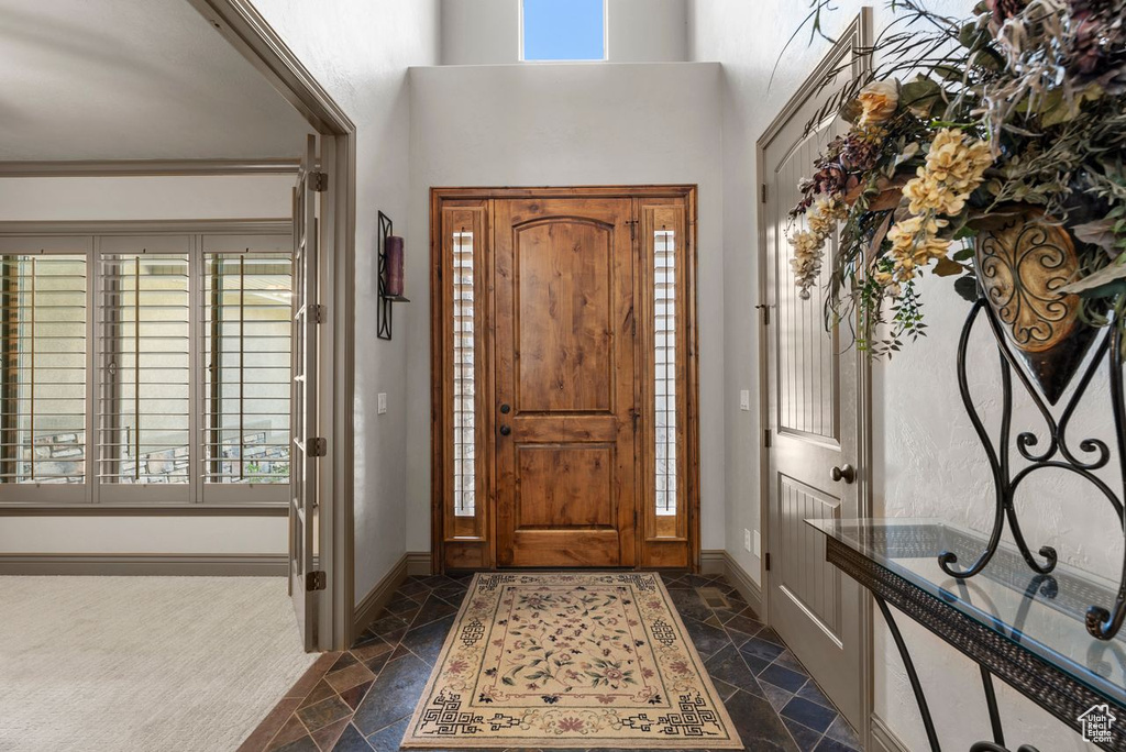 Foyer entrance with stone tile floors and a high ceiling