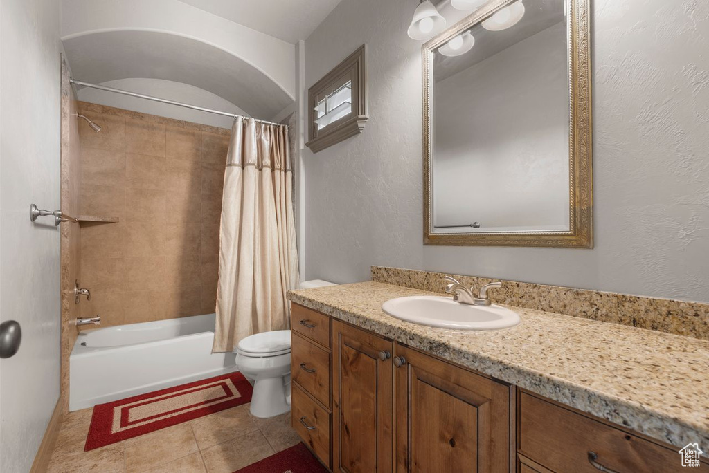 Bathroom with vanity, shower / bath combo with shower curtain, and tile patterned floors