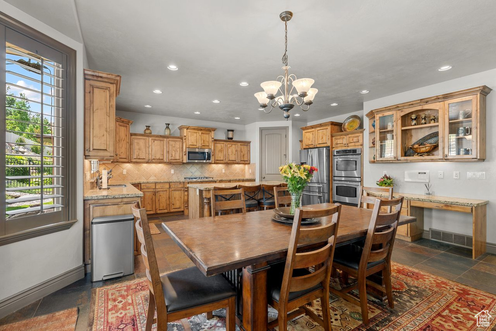 Dining room featuring recessed lighting, a chandelier, and stone tile floors