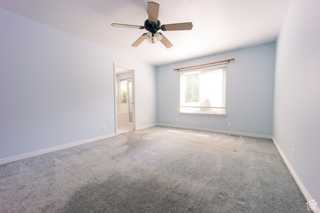 Carpeted empty room featuring a ceiling fan and baseboards