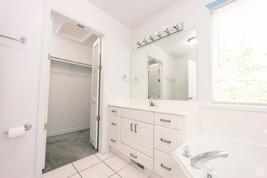 Full bath with vanity, tile patterned flooring, a garden tub, and a walk in closet
