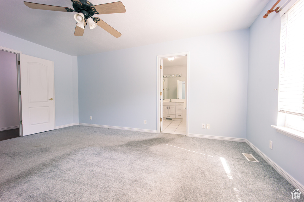 Unfurnished bedroom featuring carpet flooring, ensuite bath, and ceiling fan