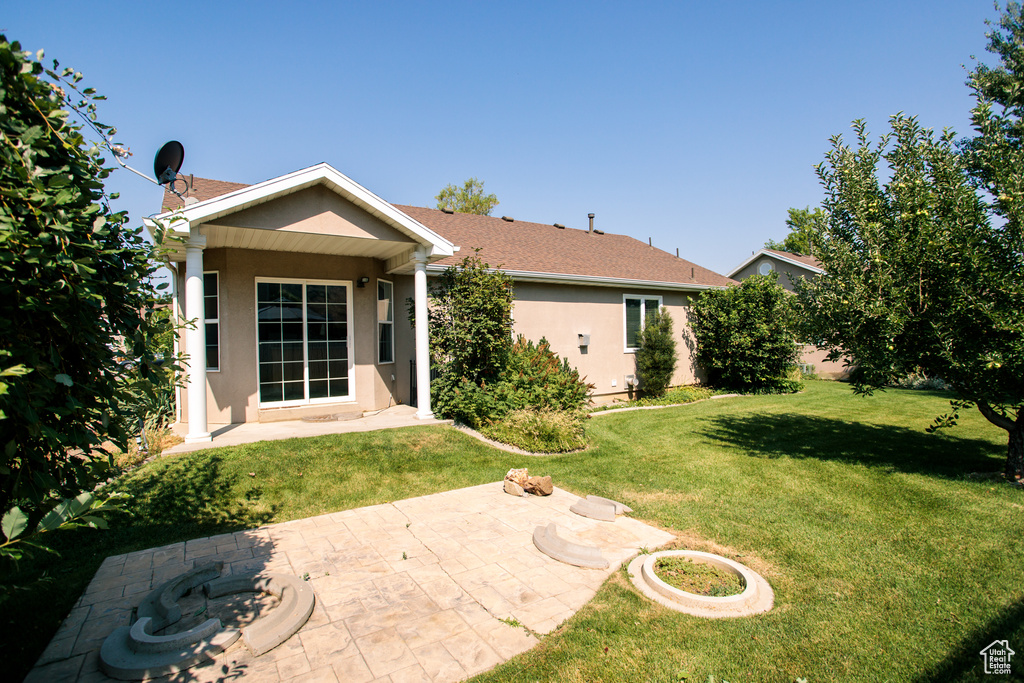 Rear view of property featuring stucco siding, a lawn, and a patio area