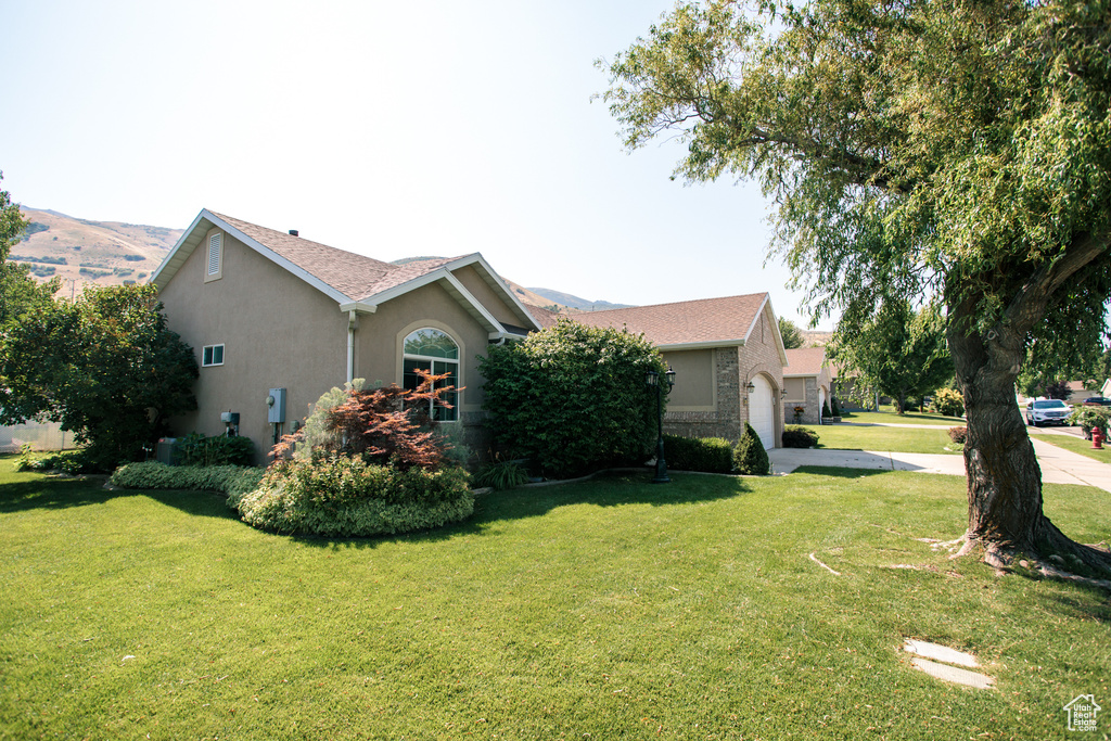 View of property exterior with stucco siding, driveway, a lawn, a garage, and a shingled roof
