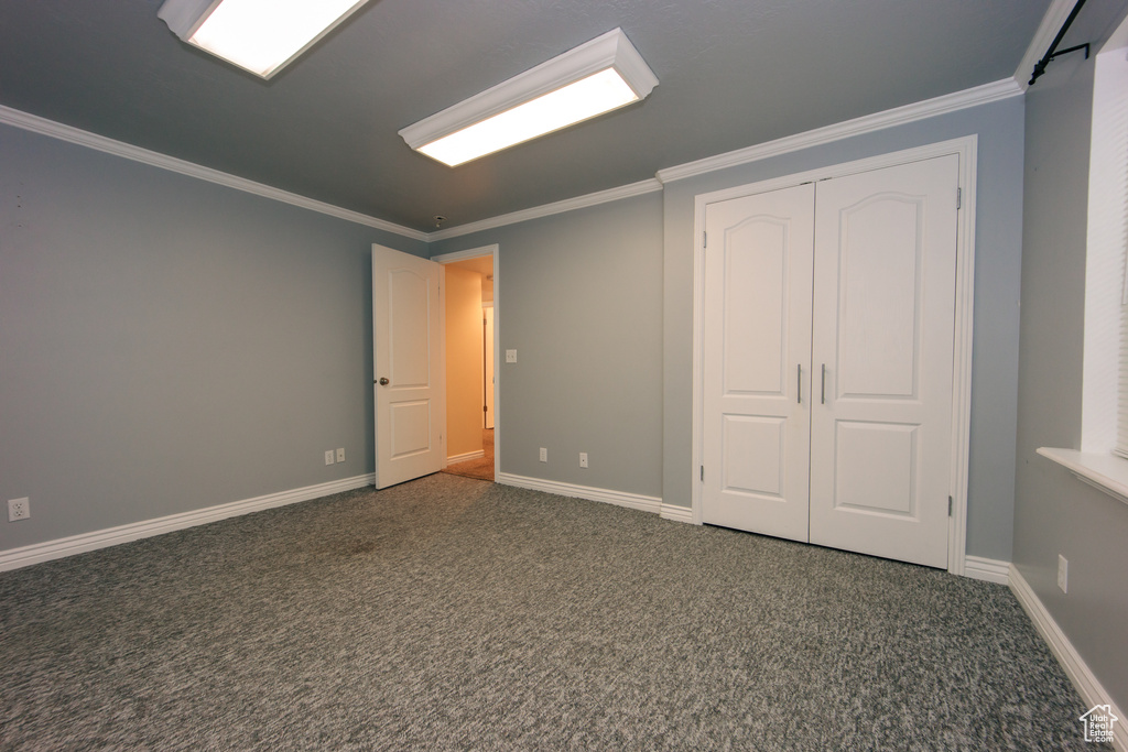 Unfurnished bedroom featuring carpet floors, ornamental molding, and a closet