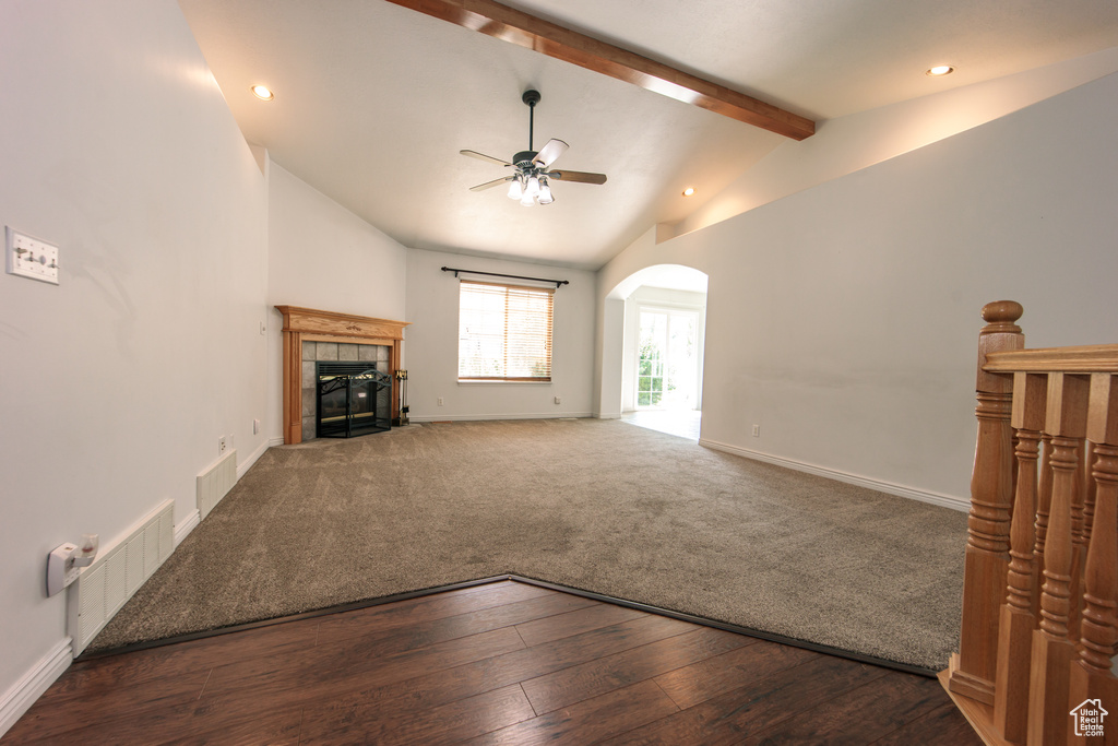 Unfurnished living room with ceiling fan, a tiled fireplace, arched walkways, wood finished floors, and recessed lighting