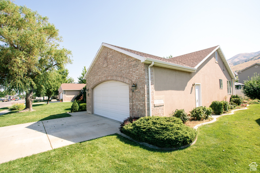 View of home\'s exterior with concrete driveway, a yard, stucco siding, brick siding, and an attached garage