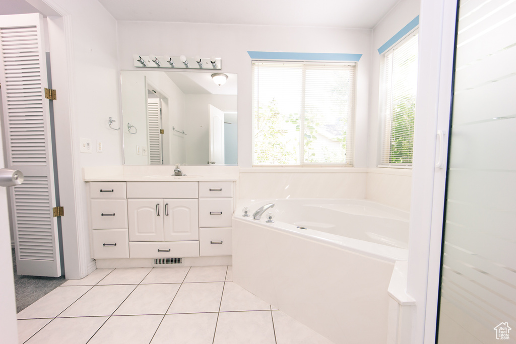 Full bath featuring vanity, a garden tub, plenty of natural light, and tile patterned floors