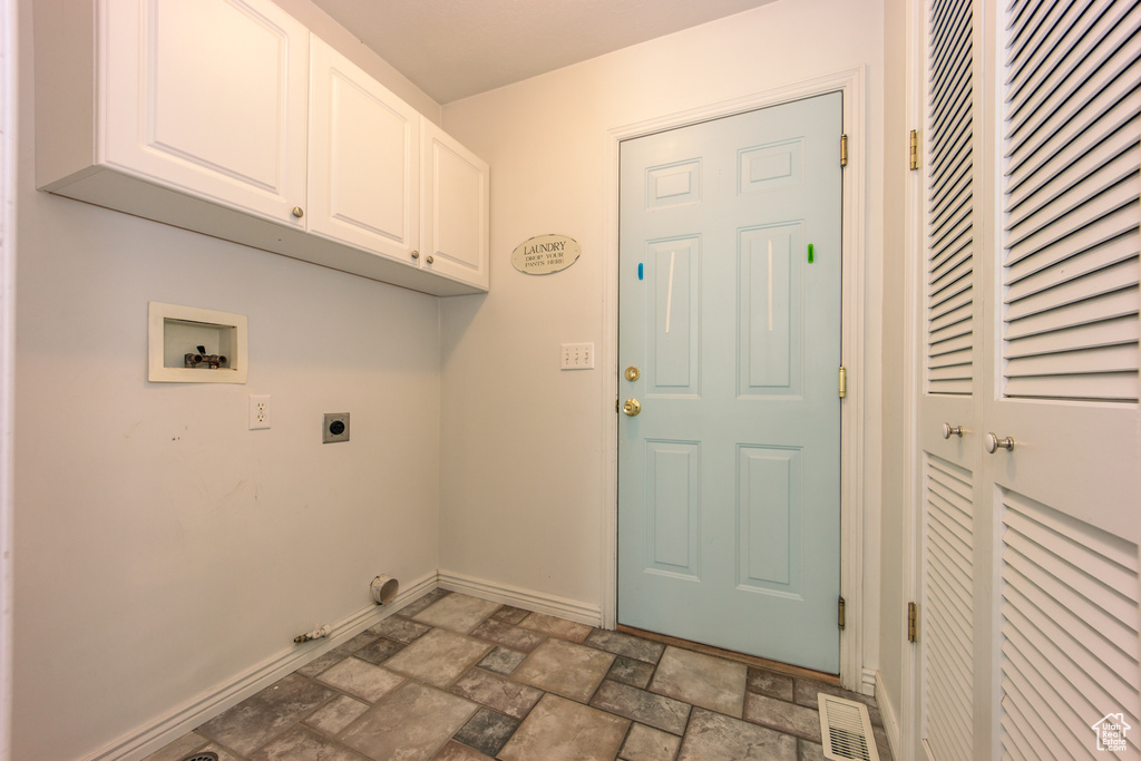 Laundry area featuring hookup for a washing machine, electric dryer hookup, cabinet space, stone finish flooring, and hookup for a gas dryer