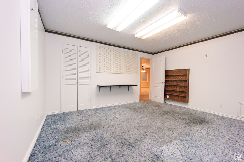 Carpeted spare room with a textured ceiling and baseboards