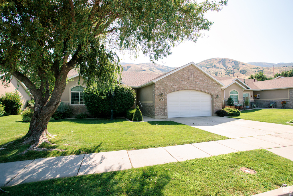 View of front facade with an attached garage, a front lawn, driveway, and a mountain view