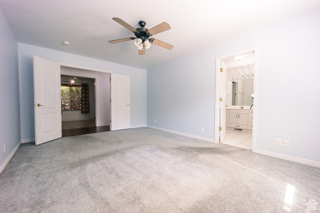 Unfurnished bedroom featuring carpet floors, ensuite bathroom, and a ceiling fan
