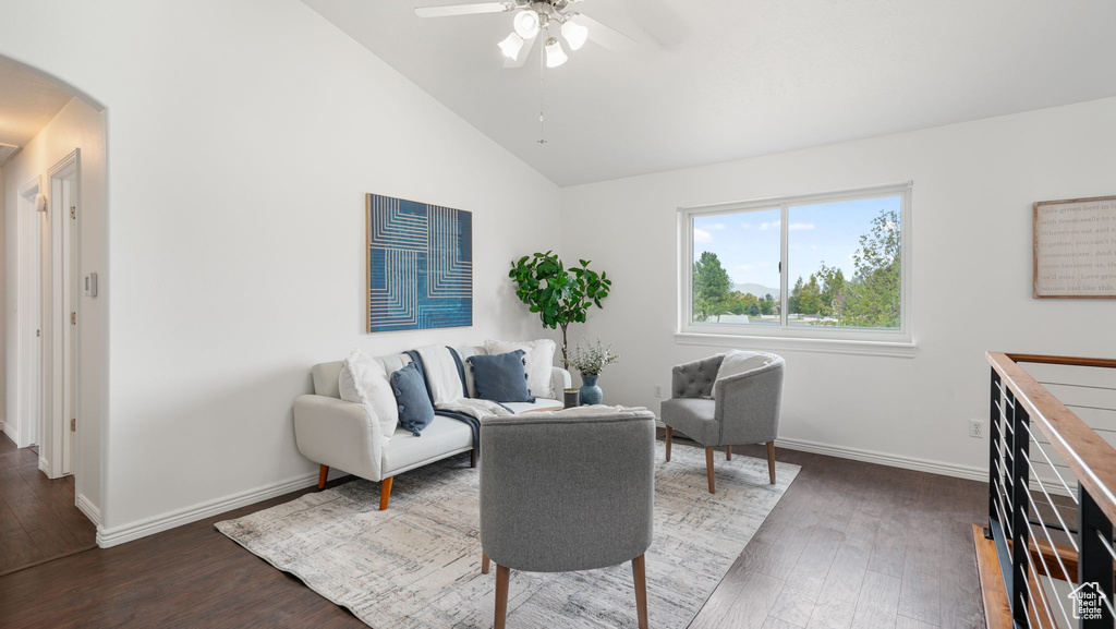 Living room featuring arched walkways, a ceiling fan, wood finished floors, and high vaulted ceiling