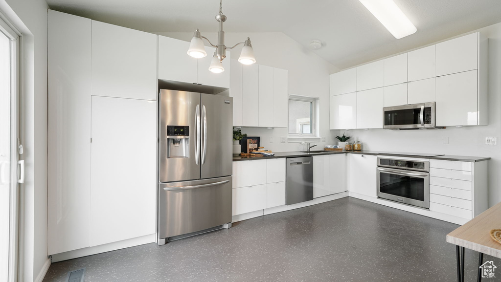 Kitchen featuring stainless steel appliances, lofted ceiling, white cabinetry, pendant lighting, and modern cabinets