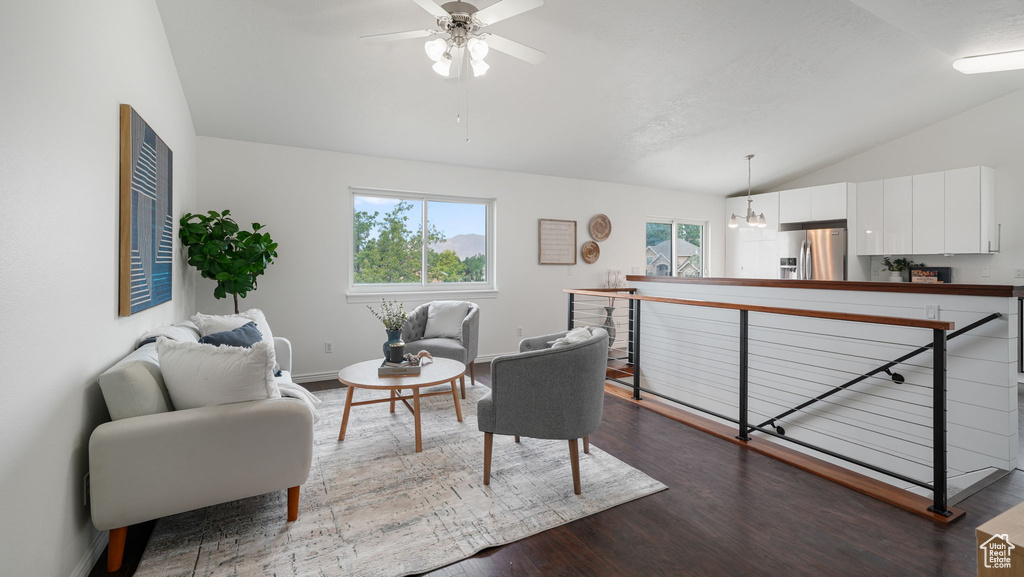 Living room with vaulted ceiling, a ceiling fan, and dark wood finished floors