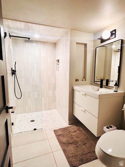 Full bathroom with vanity, tiled shower, and tile patterned flooring