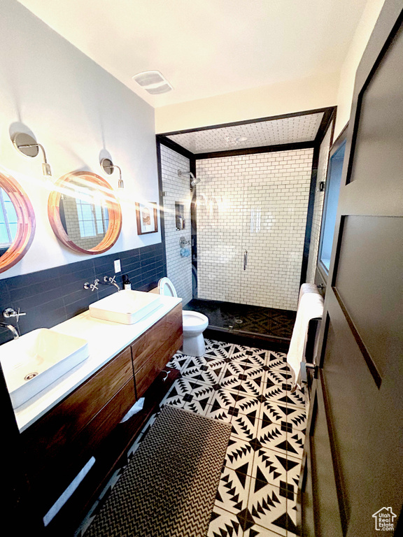 Full bathroom with a stall shower, double vanity, tile walls, and tile patterned flooring