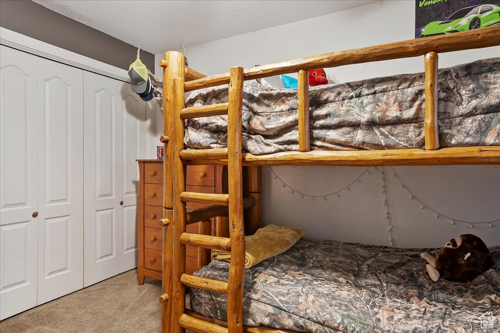 Bedroom with light colored carpet and a closet