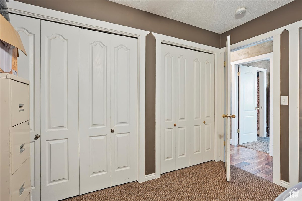 Unfurnished bedroom with carpet, two closets, and a textured ceiling