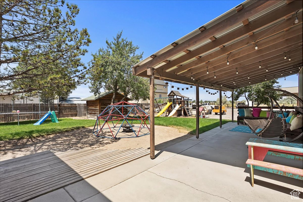 Fenced backyard featuring a playground and a patio area