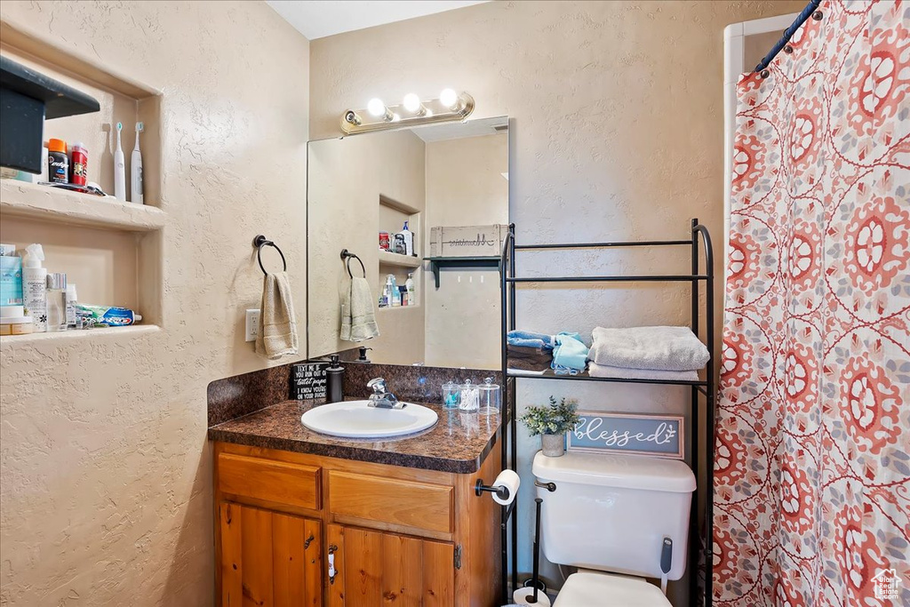 Full bathroom featuring a textured wall, vanity, and curtained shower
