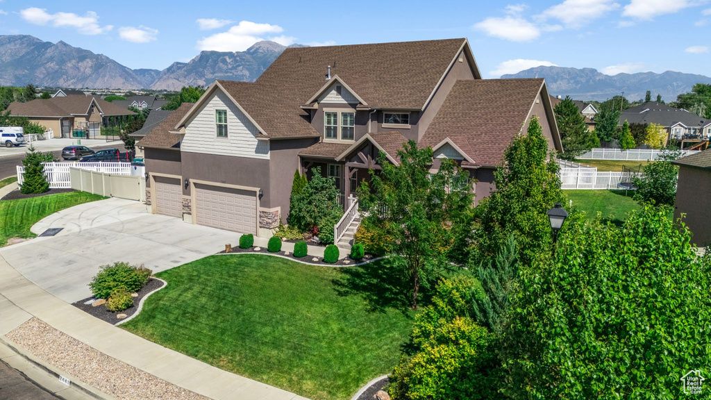 View of front facade with driveway, stucco siding, a shingled roof, and a mountain view