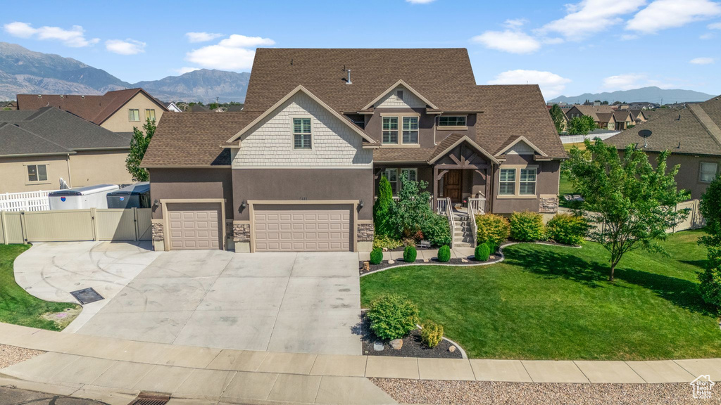 Craftsman house featuring stone siding, a mountain view, an attached garage, concrete driveway, and a gate