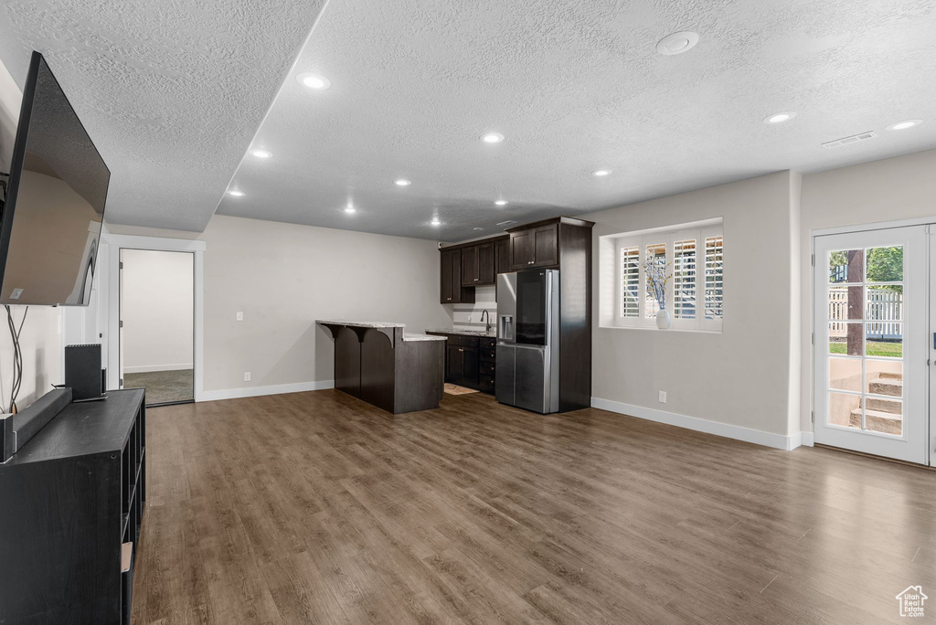 Kitchen with a textured ceiling, stainless steel fridge with ice dispenser, dark brown cabinetry, recessed lighting, and dark wood-style floors