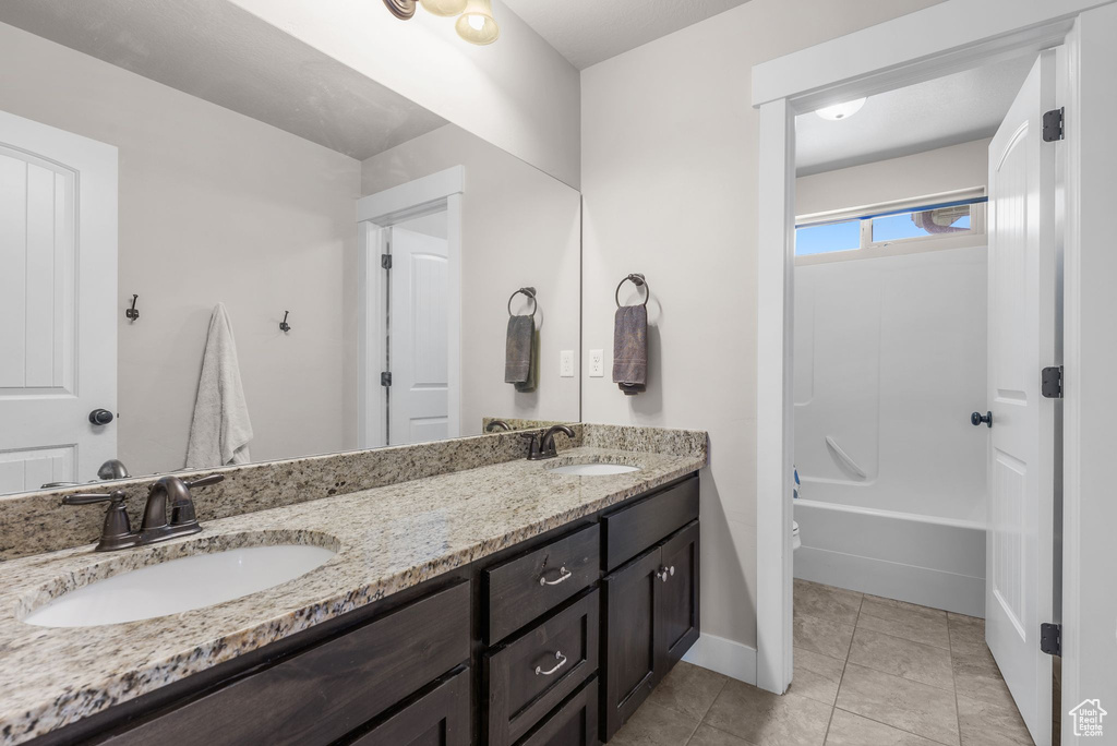 Full bath featuring double vanity, tile patterned flooring, and shower / bathtub combination
