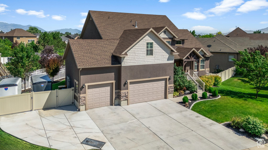 Craftsman house with a gate, roof with shingles, stone siding, stucco siding, and driveway
