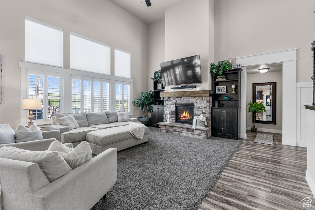Living area with a high ceiling, a stone fireplace, and wood finished floors