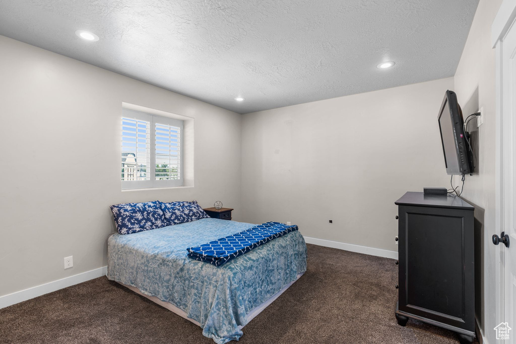 Bedroom featuring dark carpet, a textured ceiling, and recessed lighting