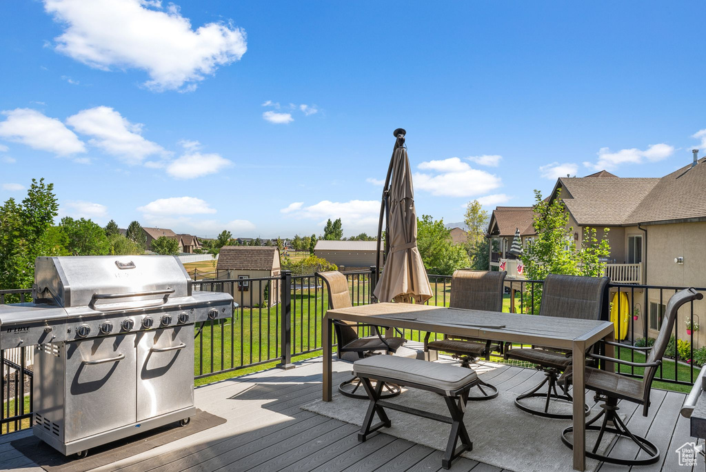 Wooden terrace featuring outdoor dining space, a grill, a yard, and a residential view