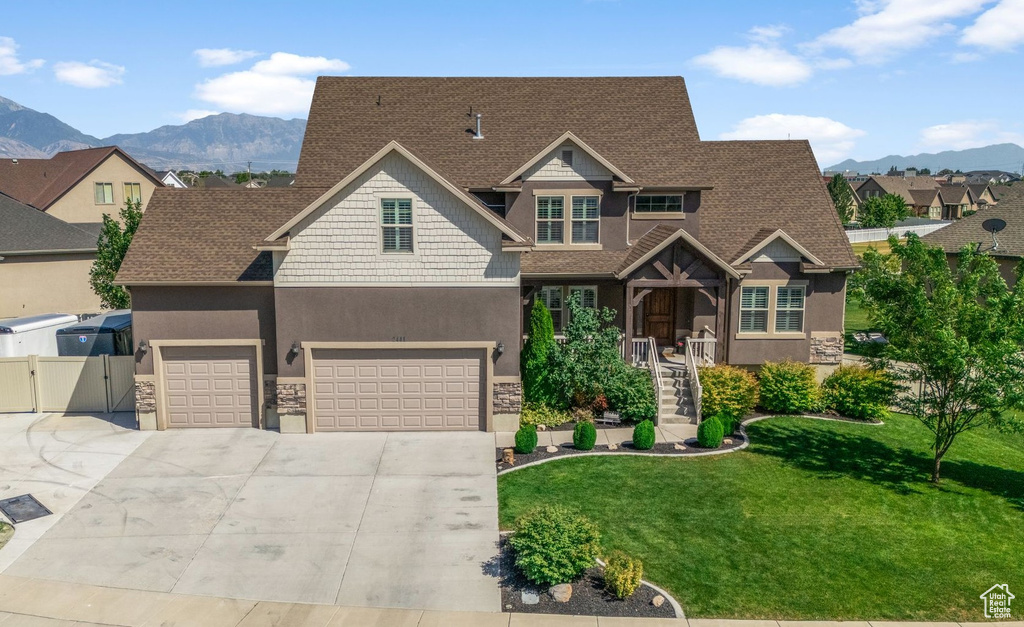 Craftsman-style house featuring a mountain view, stone siding, driveway, and a shingled roof