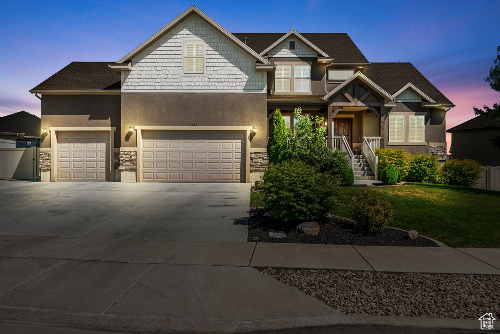 Craftsman inspired home featuring stone siding, concrete driveway, a front lawn, and stucco siding