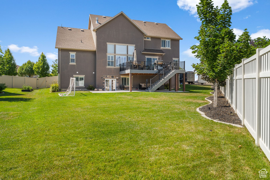 Back of property with stairway, a wooden deck, a fenced backyard, stucco siding, and roof with shingles