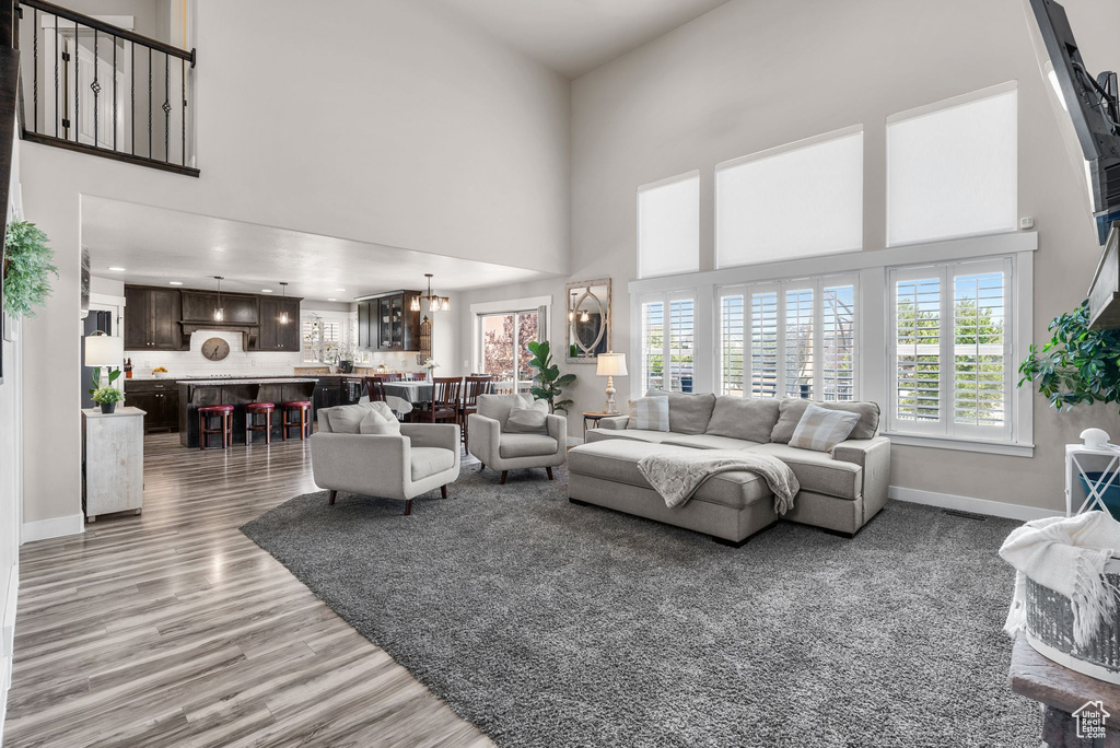 Living area with light wood-style flooring, a towering ceiling, recessed lighting, and a chandelier
