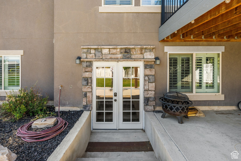 Doorway to property with french doors, stone siding, and a balcony