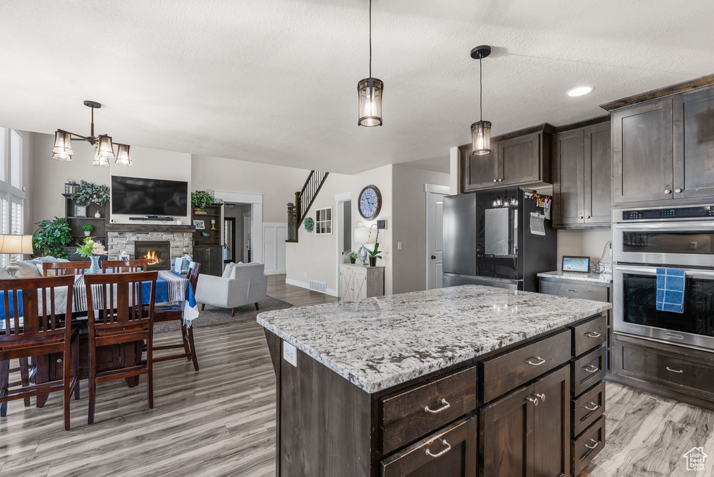 Kitchen featuring fridge, dark brown cabinetry, and light wood finished floors