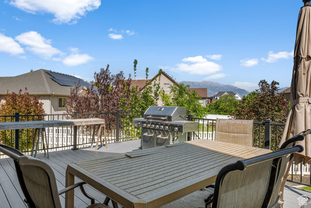 Deck with outdoor dining space, area for grilling, a residential view, and a mountain view