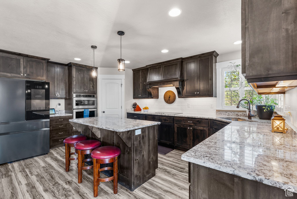 Kitchen with smart refrigerator, dark brown cabinets, a kitchen island, light wood-style floors, and recessed lighting