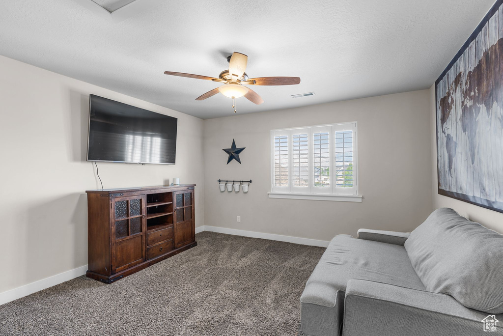 Sitting room with a ceiling fan and carpet flooring