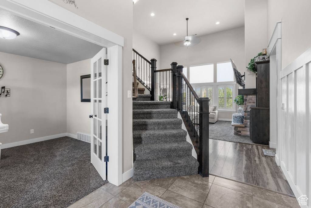 Staircase with french doors, recessed lighting, a high ceiling, and carpet floors