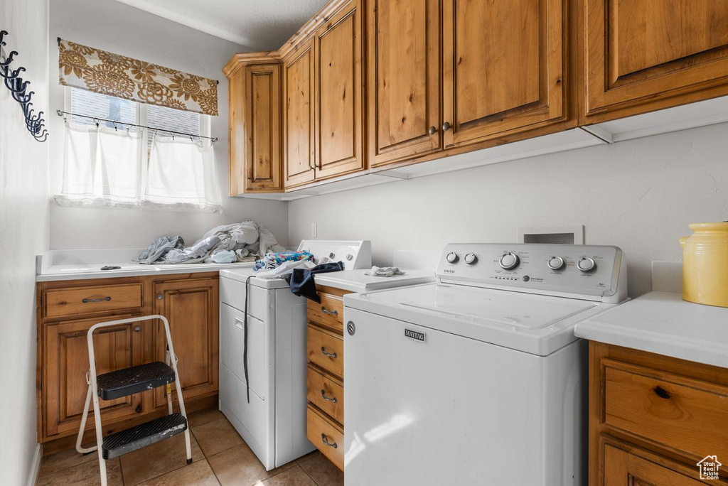 Laundry area featuring cabinet space, washing machine and dryer, and light tile patterned floors